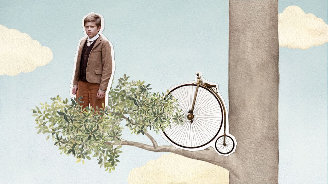 A young boy stands on a branch of a tree, dressed in vintage clothing. Next to him rests an old-fashioned penny-farthing bicycle, partially obscured by foliage, against a light blue sky with fluffy clouds.